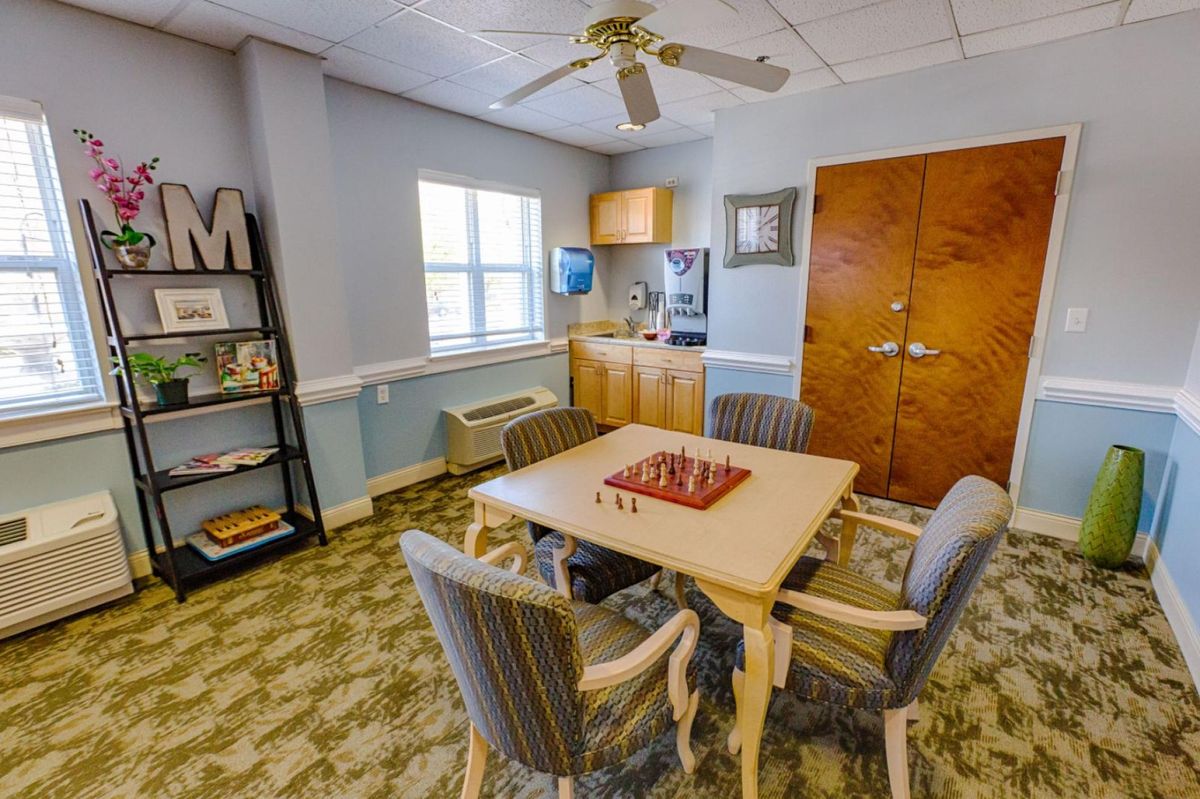 A cozy living room with a chessboard on the table and a bookshelf nearby.