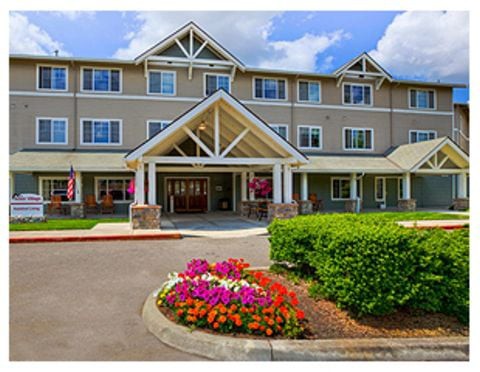 A residential building entrance with colorful flower beds and landscaping.