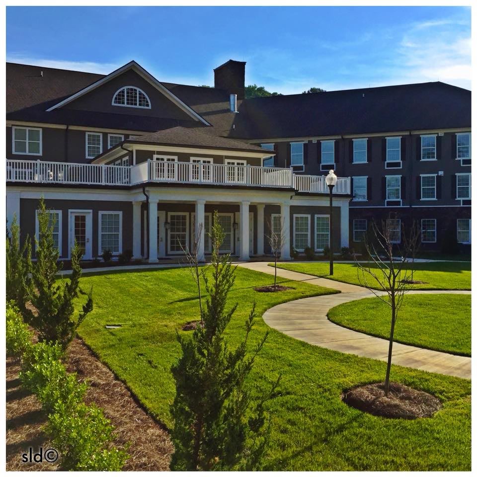 A large mansion with a well-maintained garden and pathway under a clear blue sky.