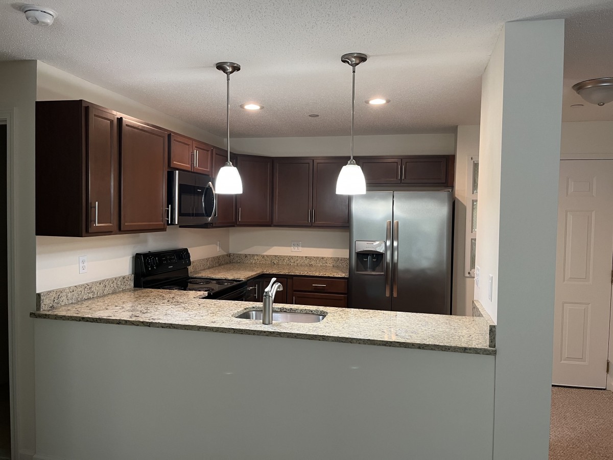 A modern kitchen with brown cabinets and stainless steel appliances.