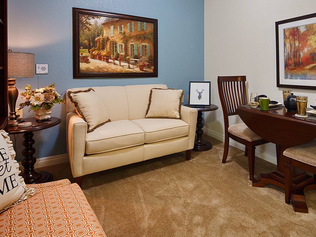 A cozy living room with a cream-colored sofa, a small round table, and wall artwork.