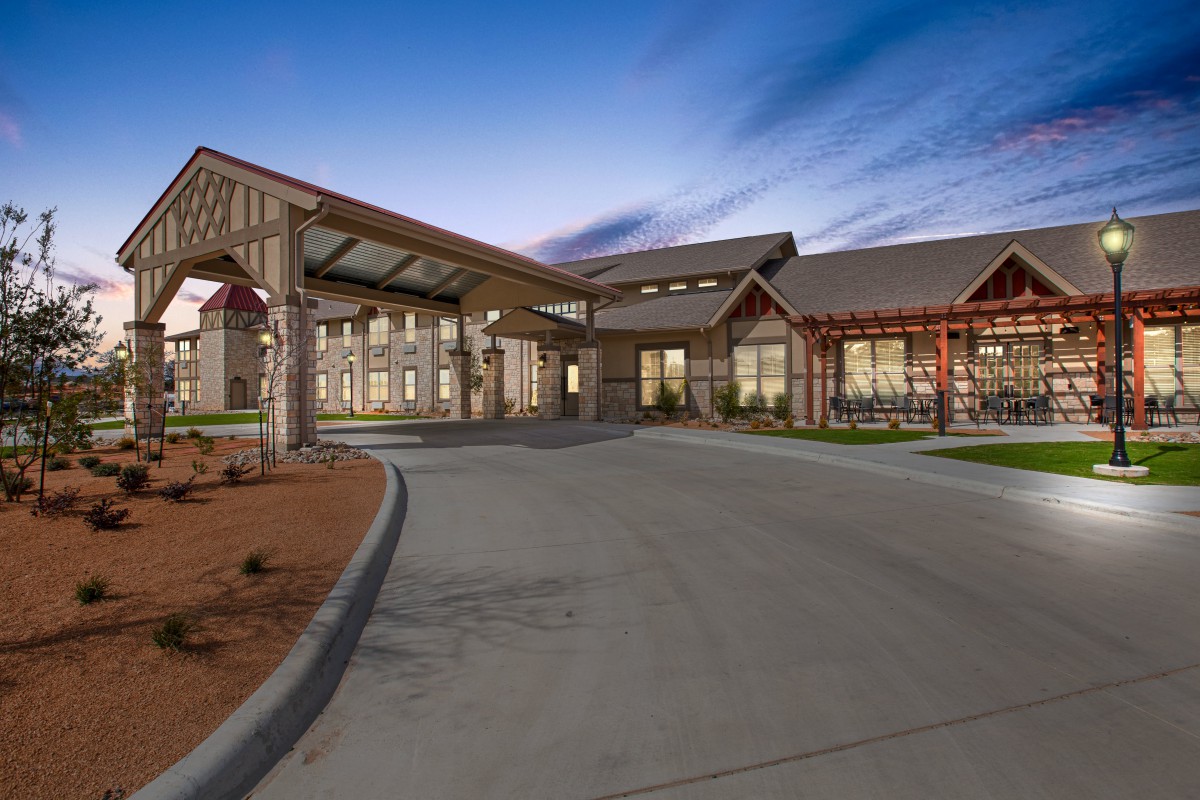 A modern building exterior with a welcoming entrance and driveway at dusk.