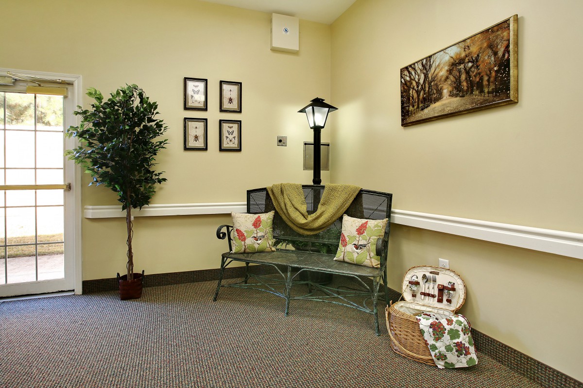 A cozy indoor setting featuring a decorative bench with pillows, an artificial plant, and wall art.
