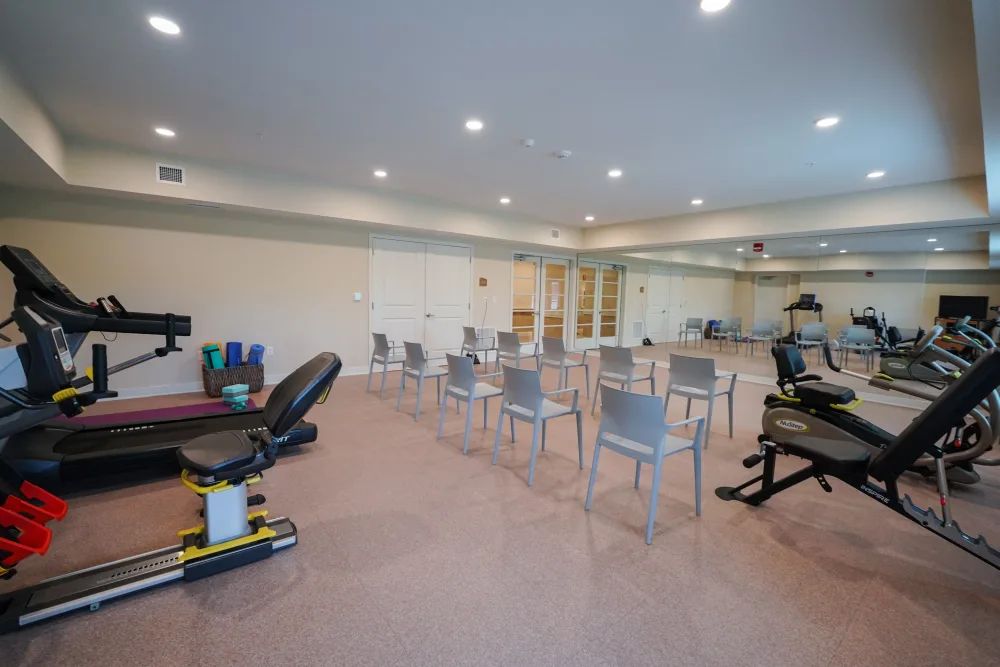 A spacious gym area with exercise equipment and seating arranged for a class.