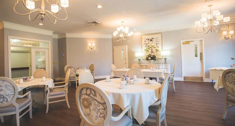 An elegantly decorated restaurant dining room with chandeliers and beautifully set tables.