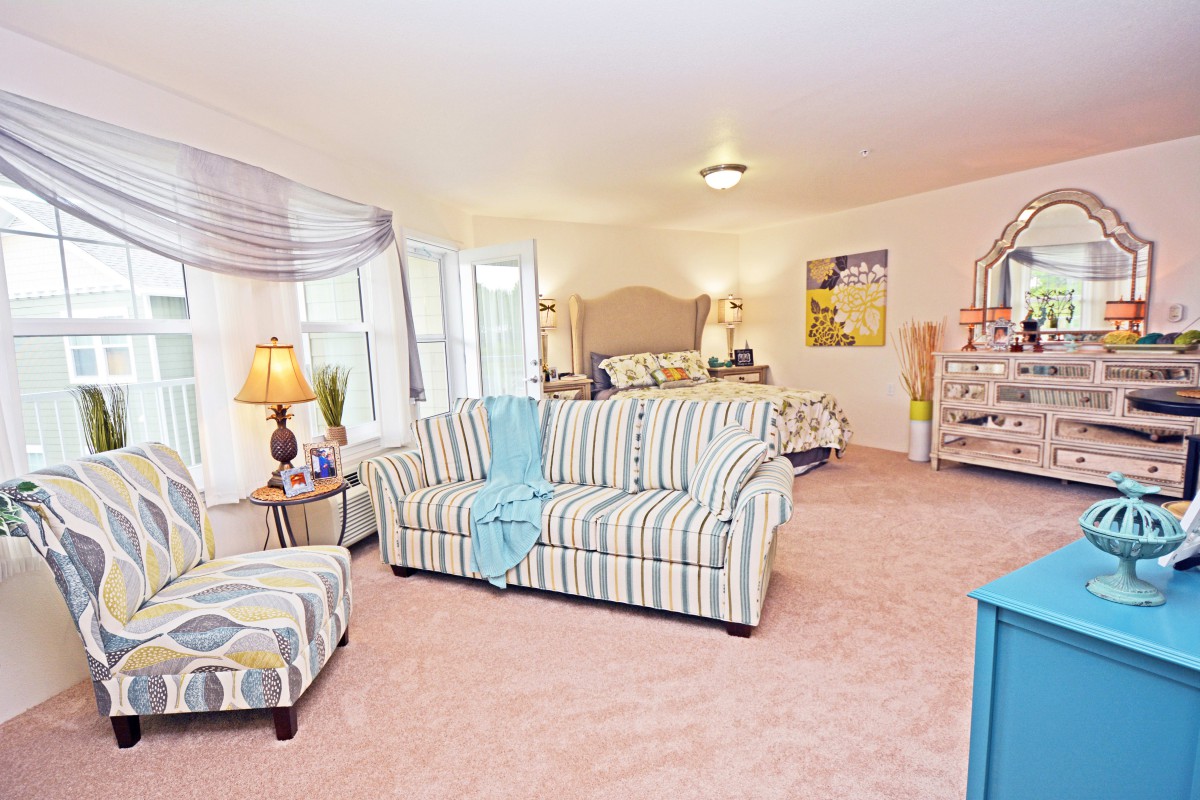 A cozy and stylish living room featuring a striped sofa, soft carpet, and tasteful decor.