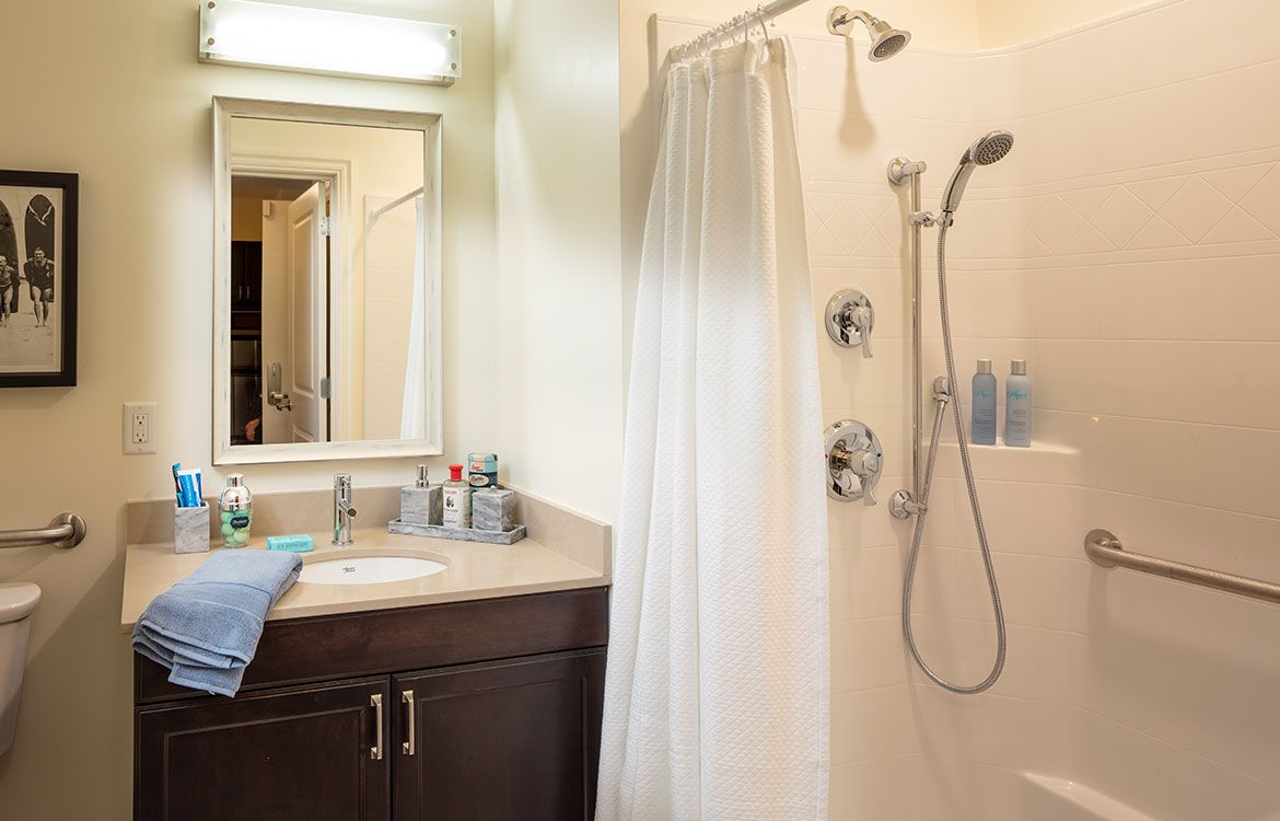 A clean and modern bathroom with a shower, sink, and mirror.