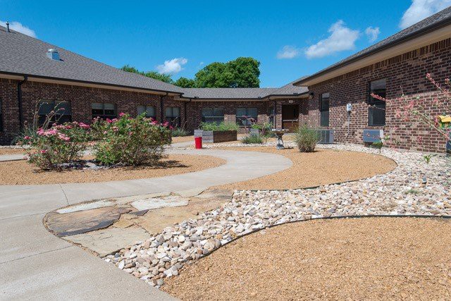A courtyard with pathways surrounded by landscaped gardens and brick buildings.
