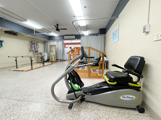 A well-equipped rehabilitation gym featuring exercise machines and a spacious area for physical therapy.