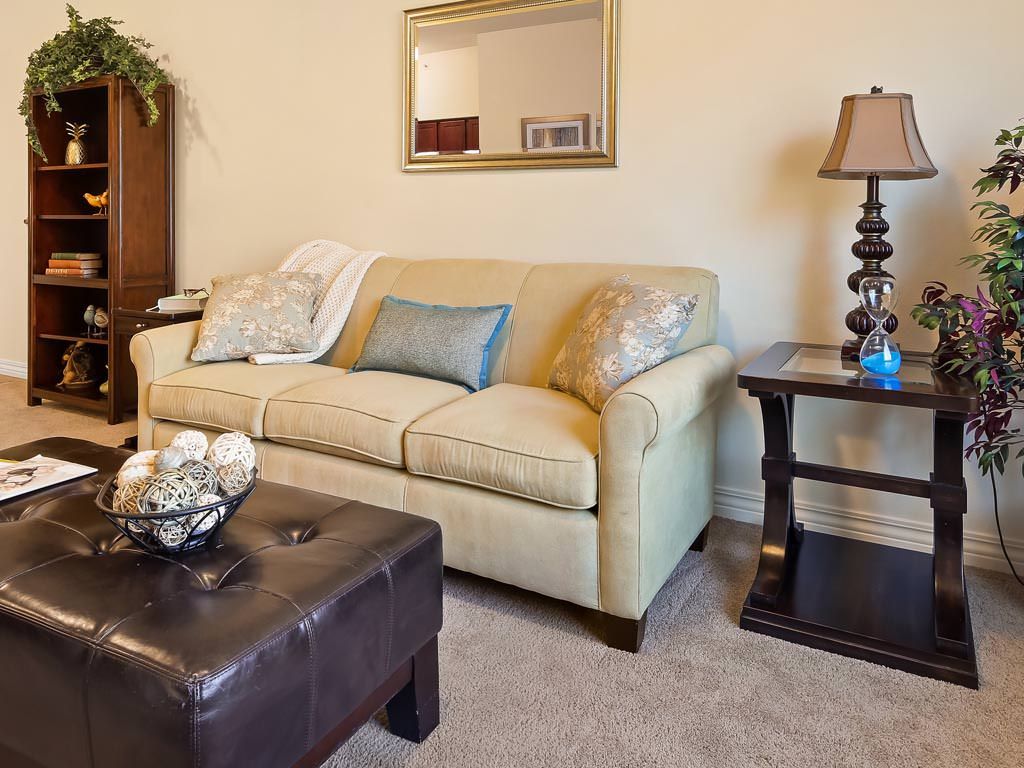 A cozy living room with a beige sofa, decorative cushions, and a stylish lamp on a side table.