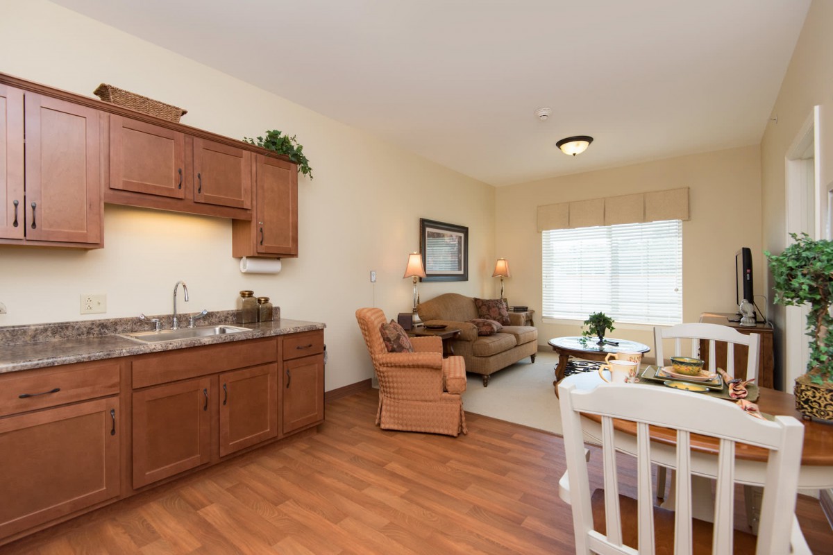 A cozy living space featuring a small kitchenette, comfortable seating, and wood flooring.