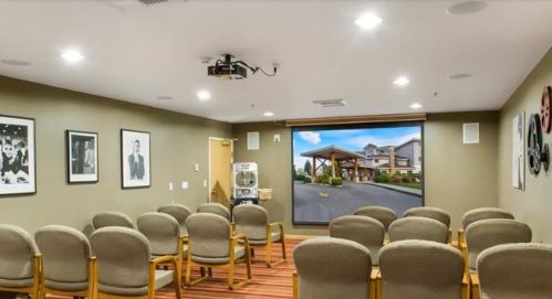 A small conference room with rows of chairs facing a projector screen displaying an image of a building entrance.