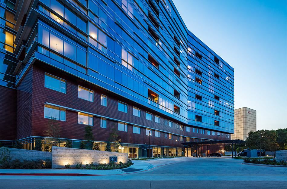 A modern hotel building with sleek design and lighting during the evening.