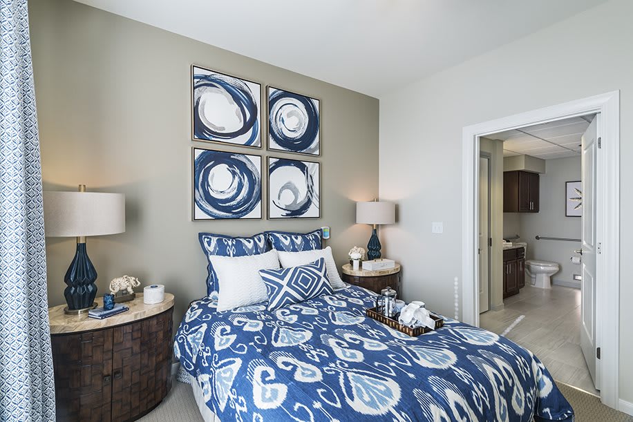 A modern bedroom with blue and white decor, featuring abstract art and stylish bedding.
