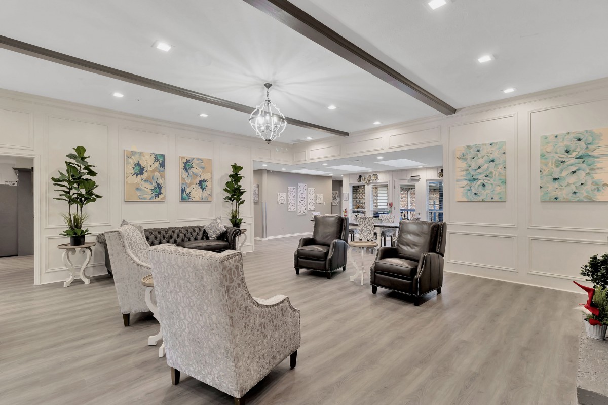 A modern living room with elegant furniture and decor, featuring a chandelier and artwork.