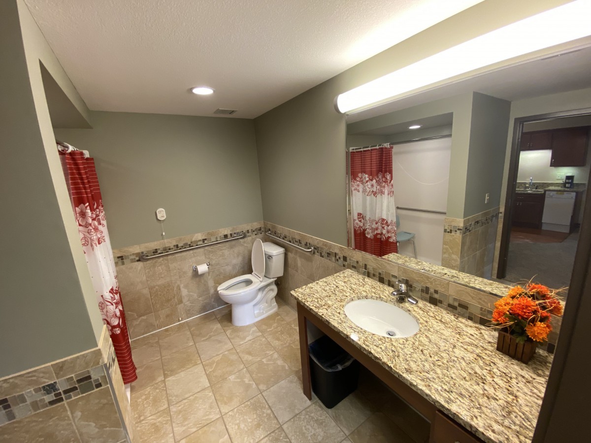 A modern bathroom featuring a granite countertop, tiled flooring, and a shower curtain.