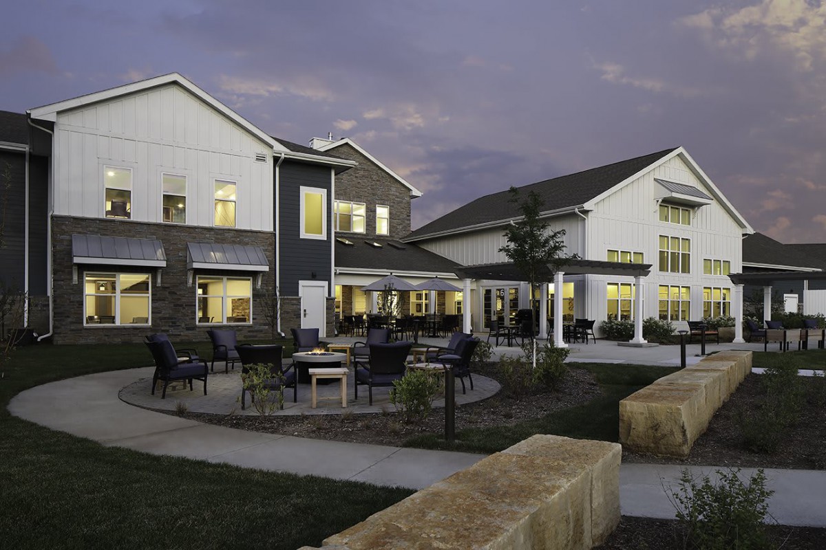 A modern building with outdoor seating illuminated in the evening.