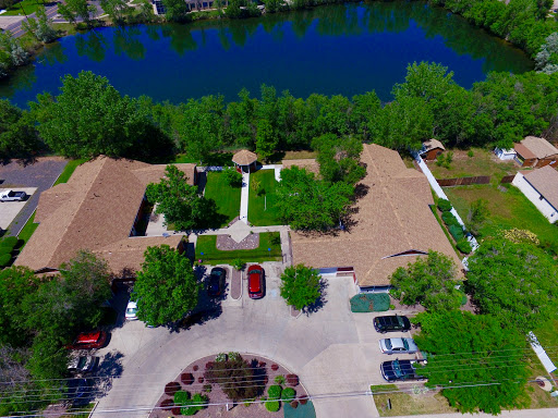 Aerial view of a serene landscape featuring buildings surrounded by lush greenery and a calm water body.