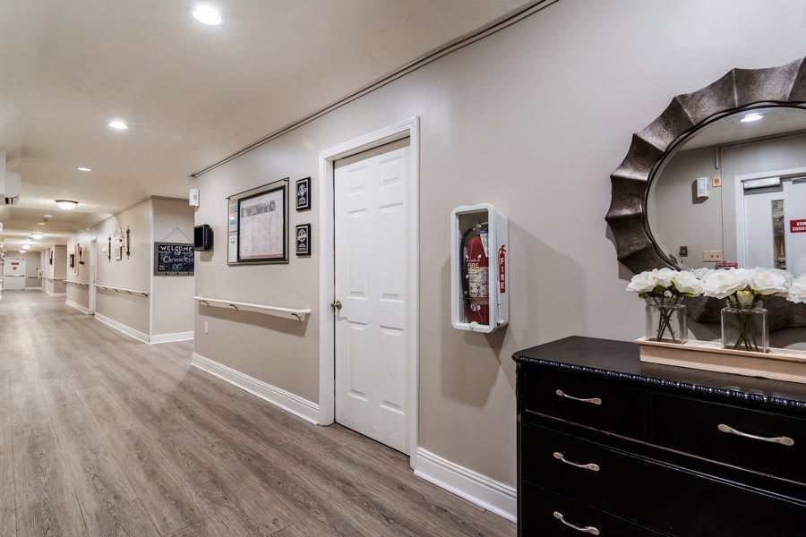 A modern hallway with framed pictures and a fire extinguisher on the wall, featuring a wooden cabinet and mirror.