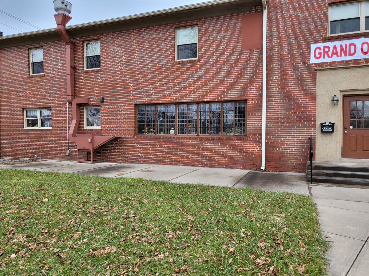 A brick building with windows and a sign, surrounded by a grassy area.