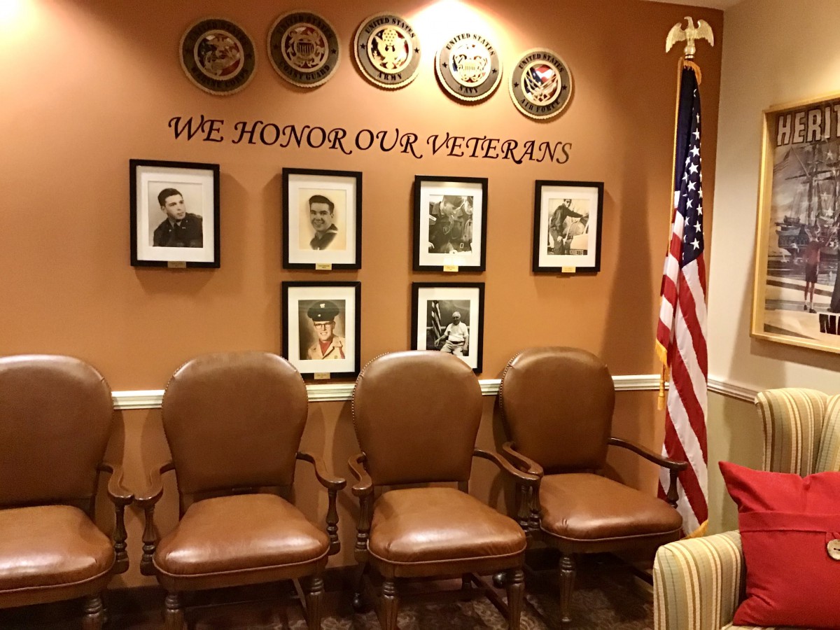 A room featuring portraits and symbols honoring veterans, with three chairs and an American flag prominently displayed.