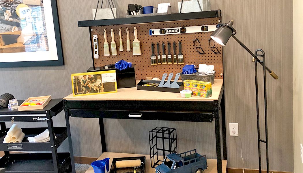 A workbench with various tools and gifts, including paintbrushes and a toy truck.