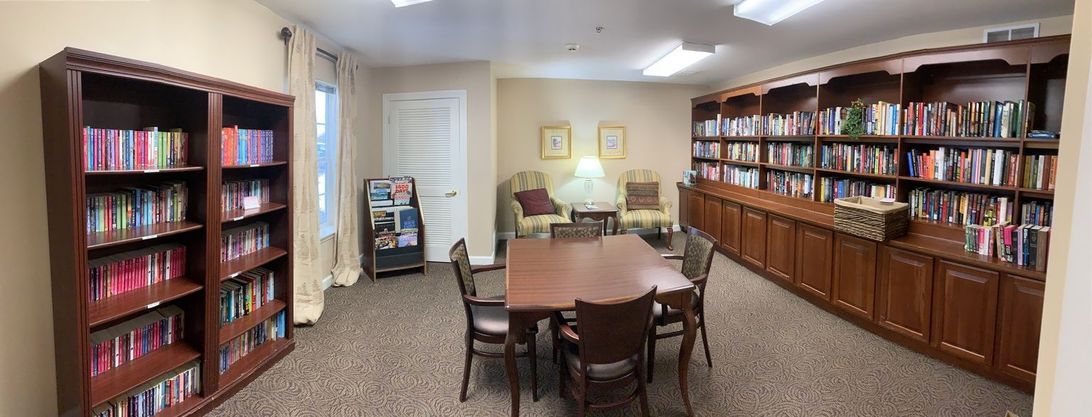 A cozy reading area with a table, chairs, bookshelves, and comfortable seating.