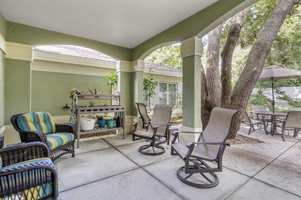 A cozy covered patio with comfortable seating and potted plants, perfect for relaxation.