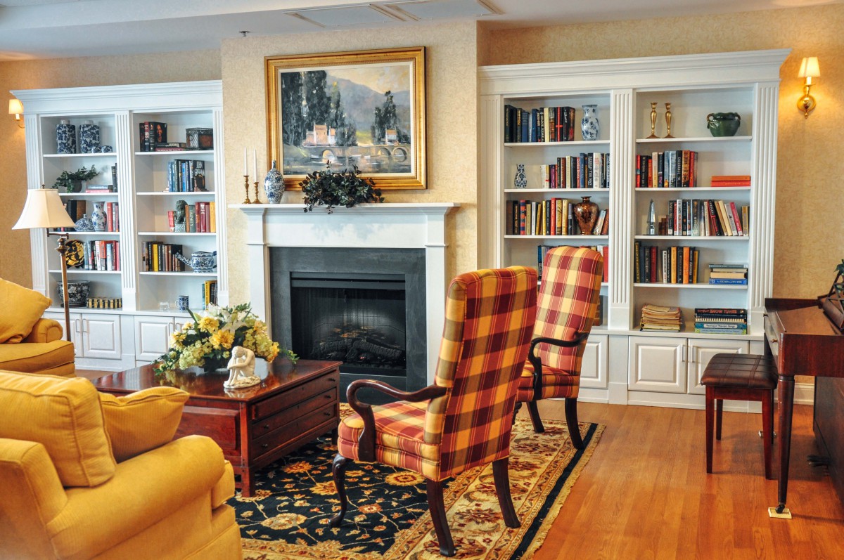 A cozy living room with a fireplace surrounded by built-in bookshelves and patterned armchairs.
