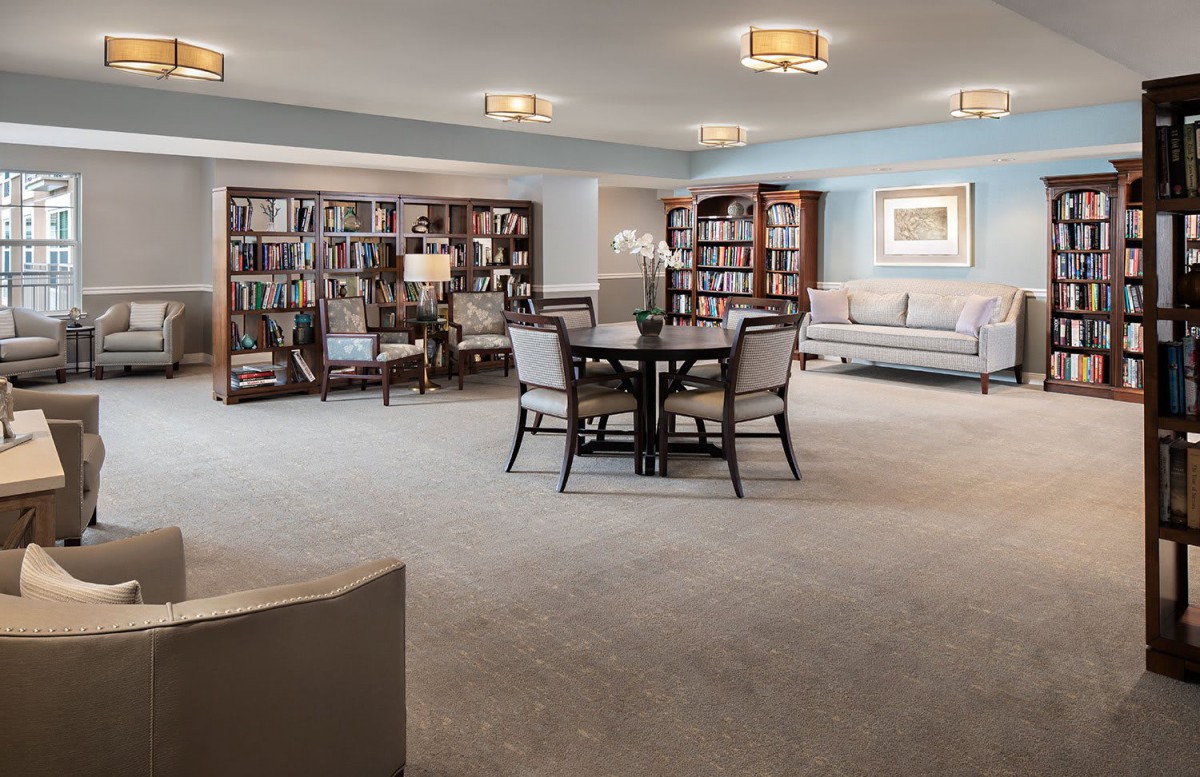 A cozy and spacious library room with bookshelves, a reading table, and comfortable seating.