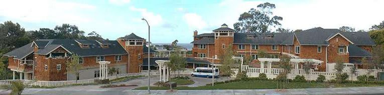 A scenic view of a brick building near the street with a bus parked in front and trees lining the area.
