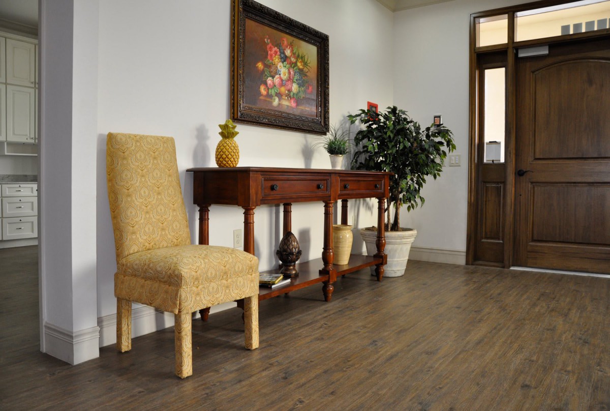 A cozy interior featuring a wooden console table with decorative items and a plant, alongside an upholstered chair.