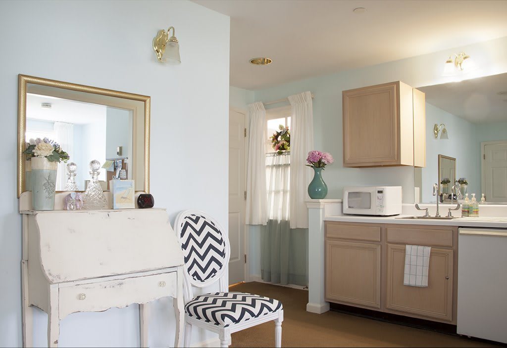 A cozy kitchen space with a zigzag patterned chair, wooden cabinets, and a decorative mirror.