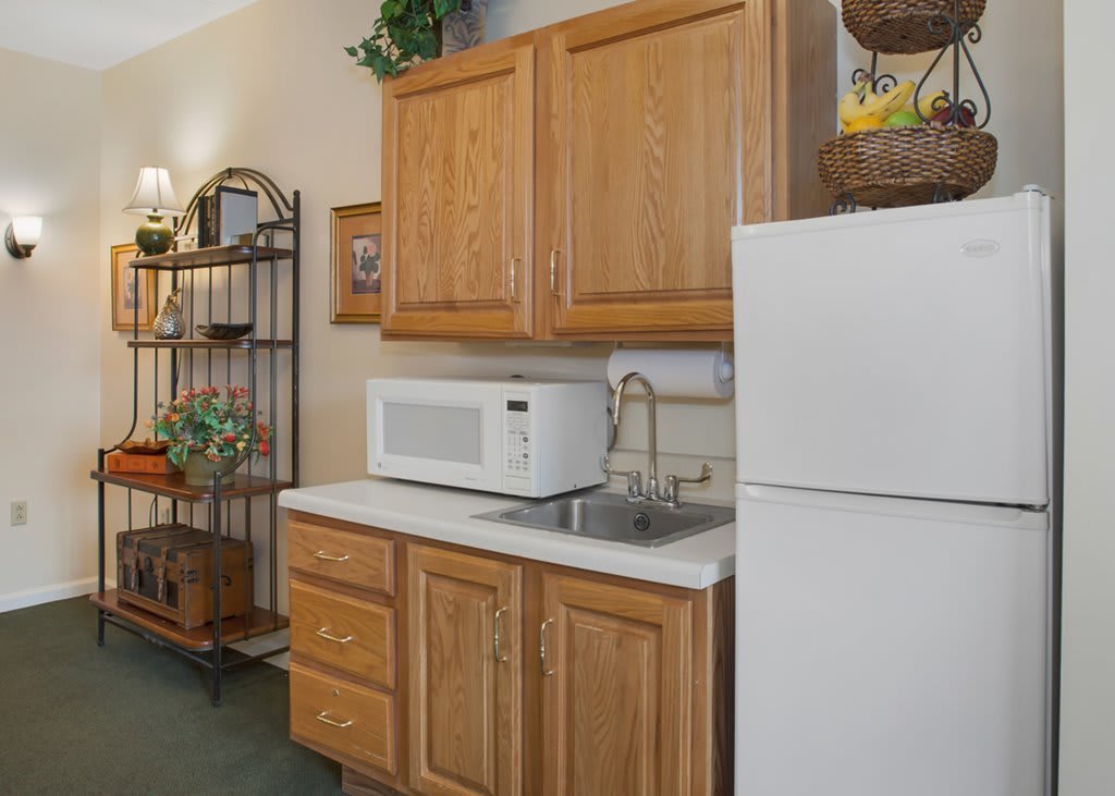 A compact kitchen area with wooden cabinets, a white refrigerator, and a microwave on the countertop.