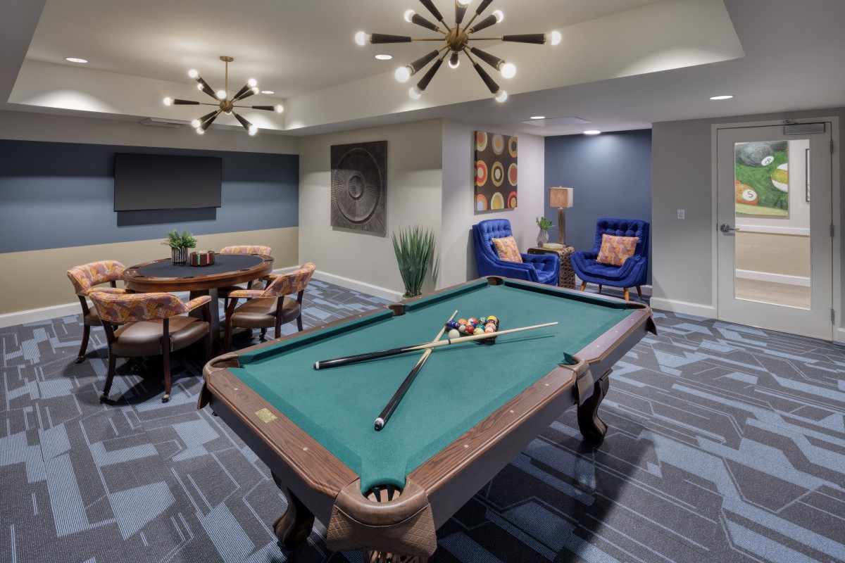 A stylish game room featuring a pool table and modern seating area with elegant lighting.