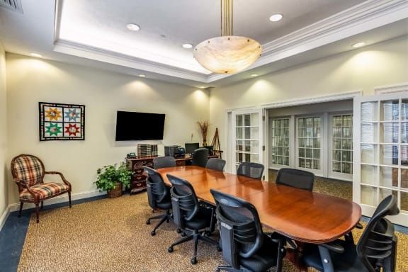 A well-lit conference room with a large wooden table surrounded by black office chairs.