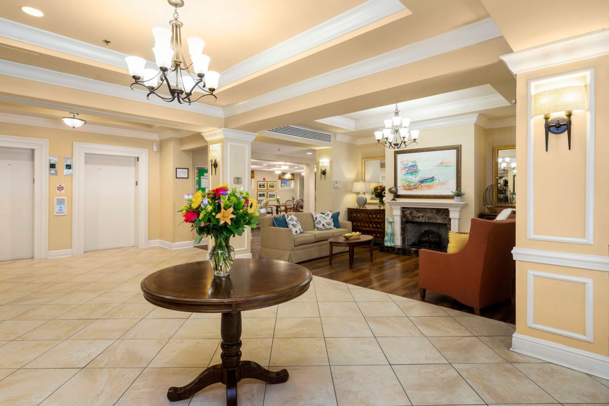 Elegant lobby with a central table and floral arrangement, featuring comfortable seating and a fireplace.