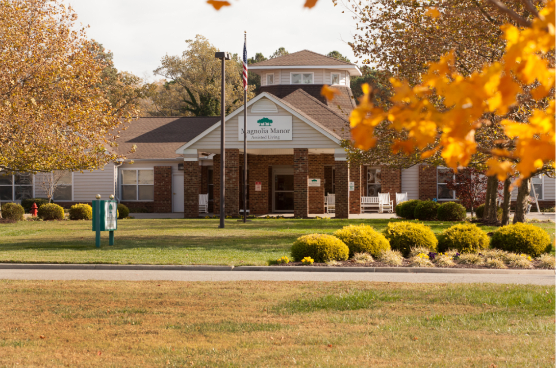 A brick building surrounded by autumn foliage and a well-maintained lawn.