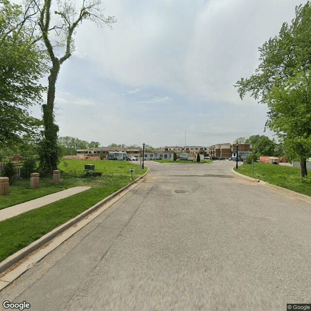 A quiet suburban street lined with trees and well-maintained lawns on a clear day.