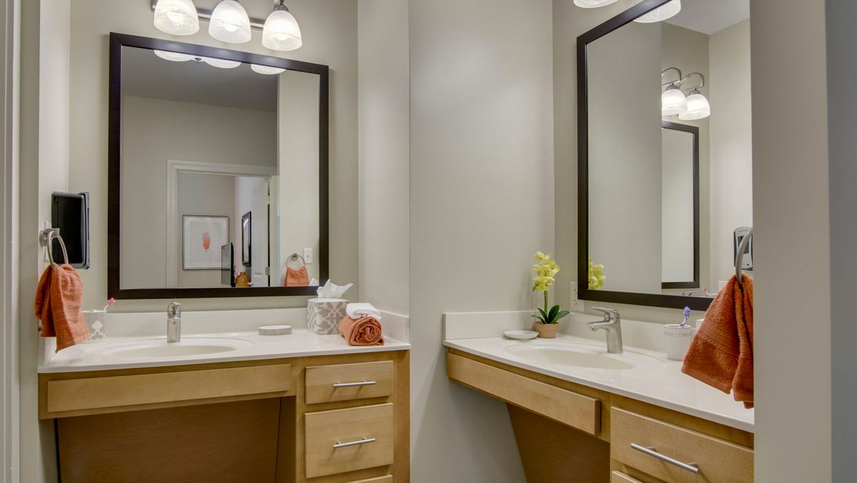 A modern bathroom with dual mirrors and sinks, featuring minimalist decor and bright lighting.