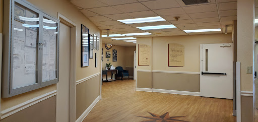 A well-lit office hallway featuring wall decorations and a comfortable seating area.