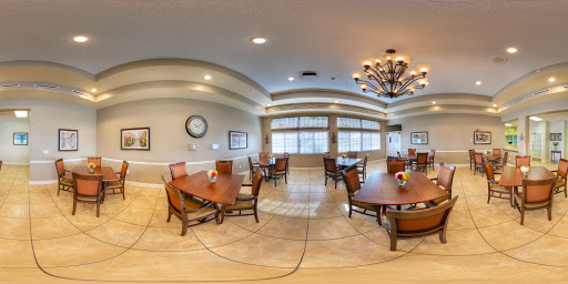 A spacious dining area with elegant decor, featuring wooden tables and chairs, accented by a beautiful chandelier.