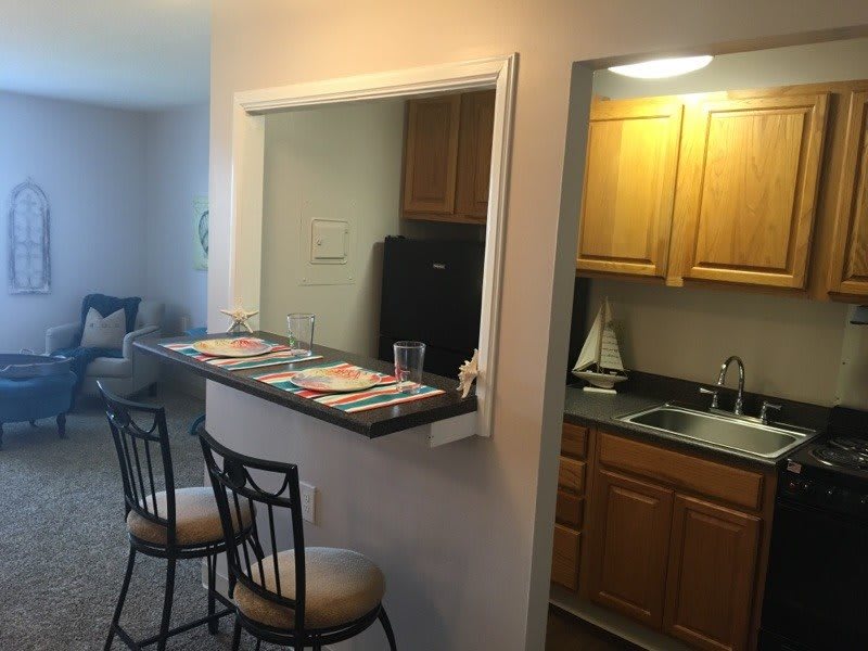 A cozy apartment kitchen with bar stools and a pass-through counter.