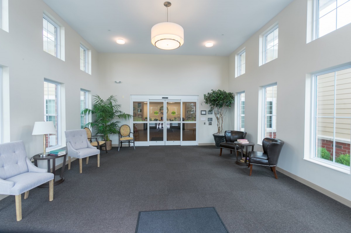 A bright and spacious lobby with seating, decorative plants, and a central chandelier.
