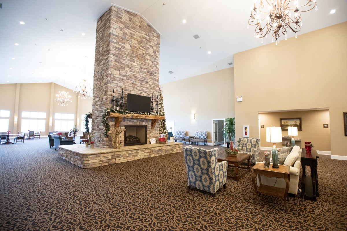 A spacious living room featuring a large stone fireplace, comfortable seating, and elegant lighting.