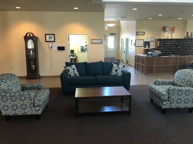 A cozy living room setup with a couch, chairs, coffee table, and a grandfather clock.