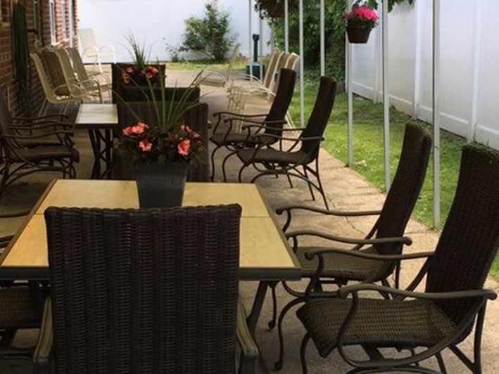Outdoor patio seating area with tables and chairs surrounded by plants.