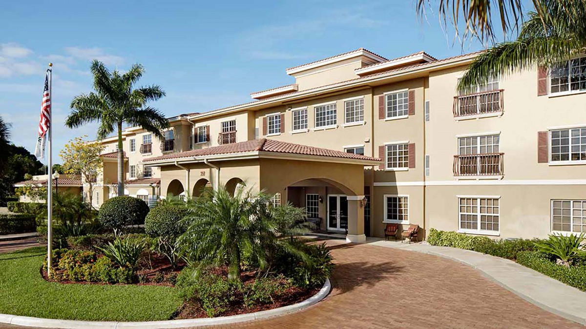 A well-maintained residential building with palm trees and a landscaped entrance.