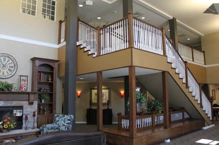 A spacious living area featuring a prominent wooden staircase and balcony.