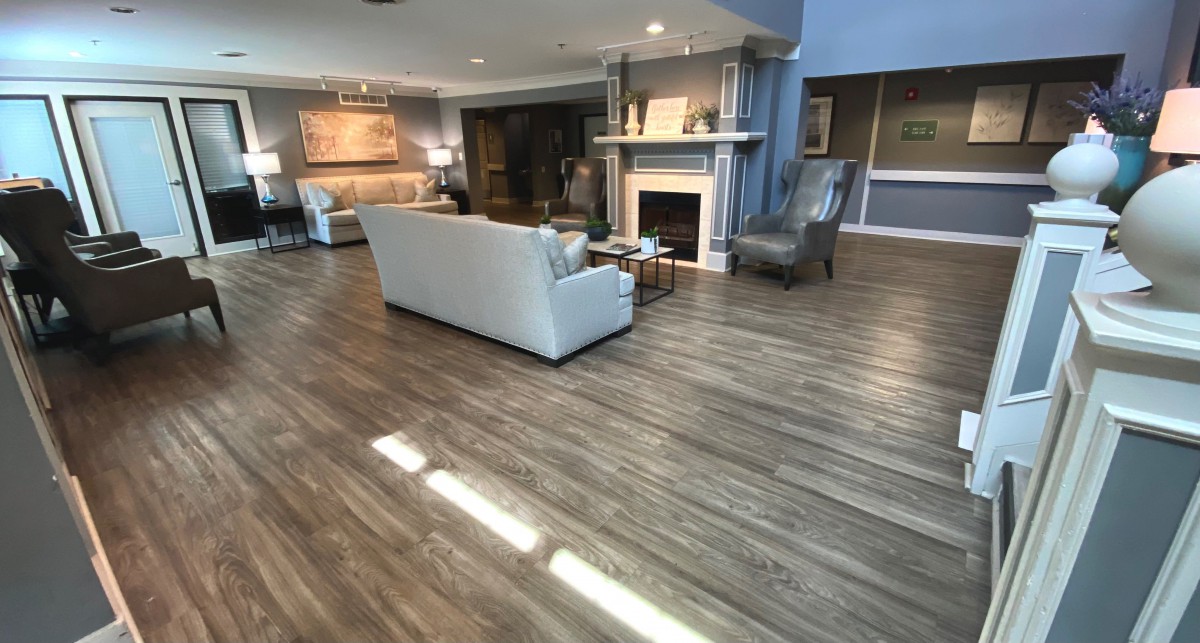 A spacious and elegantly decorated living room featuring wood flooring, a cozy sofa, and a fireplace.